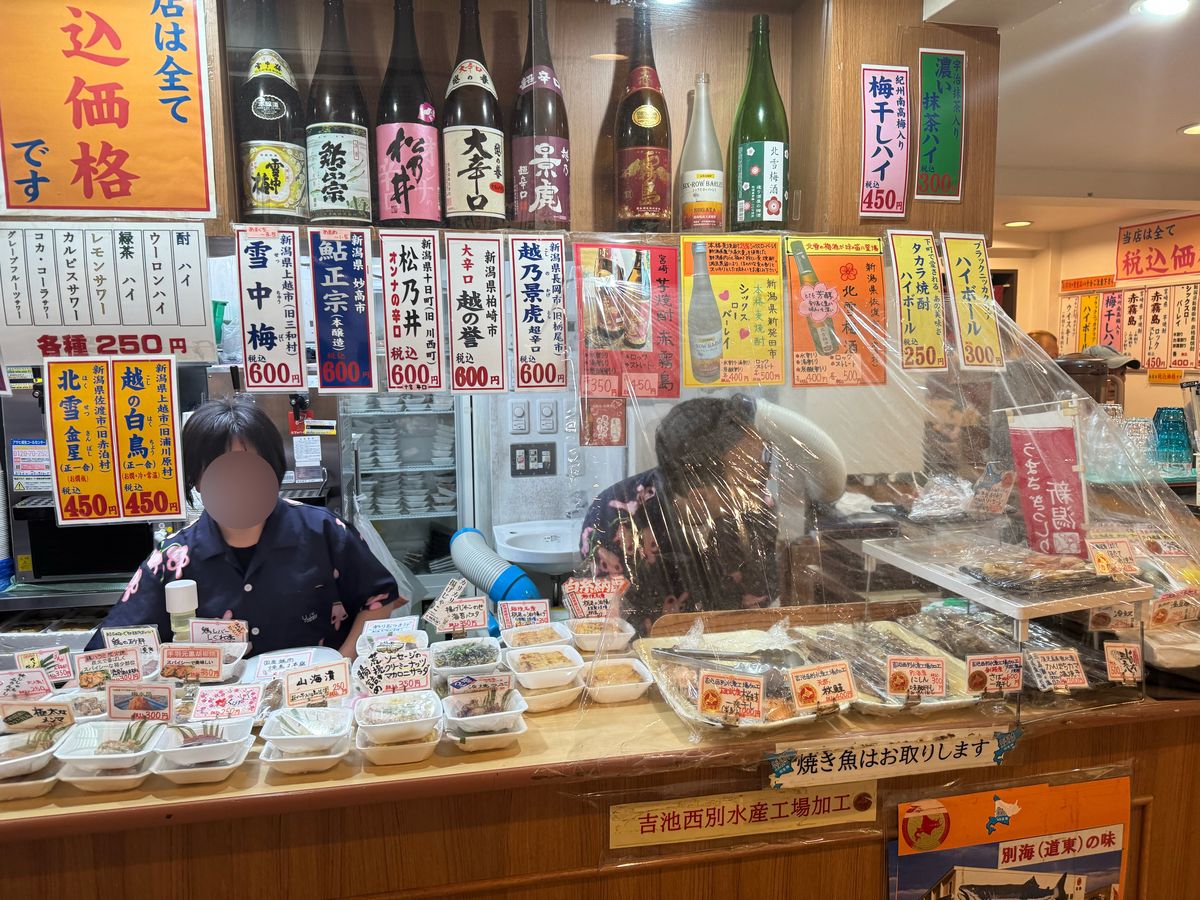 味の笛の日本酒コーナー。新潟の日本酒が棚に並び、店員が奥で調理している