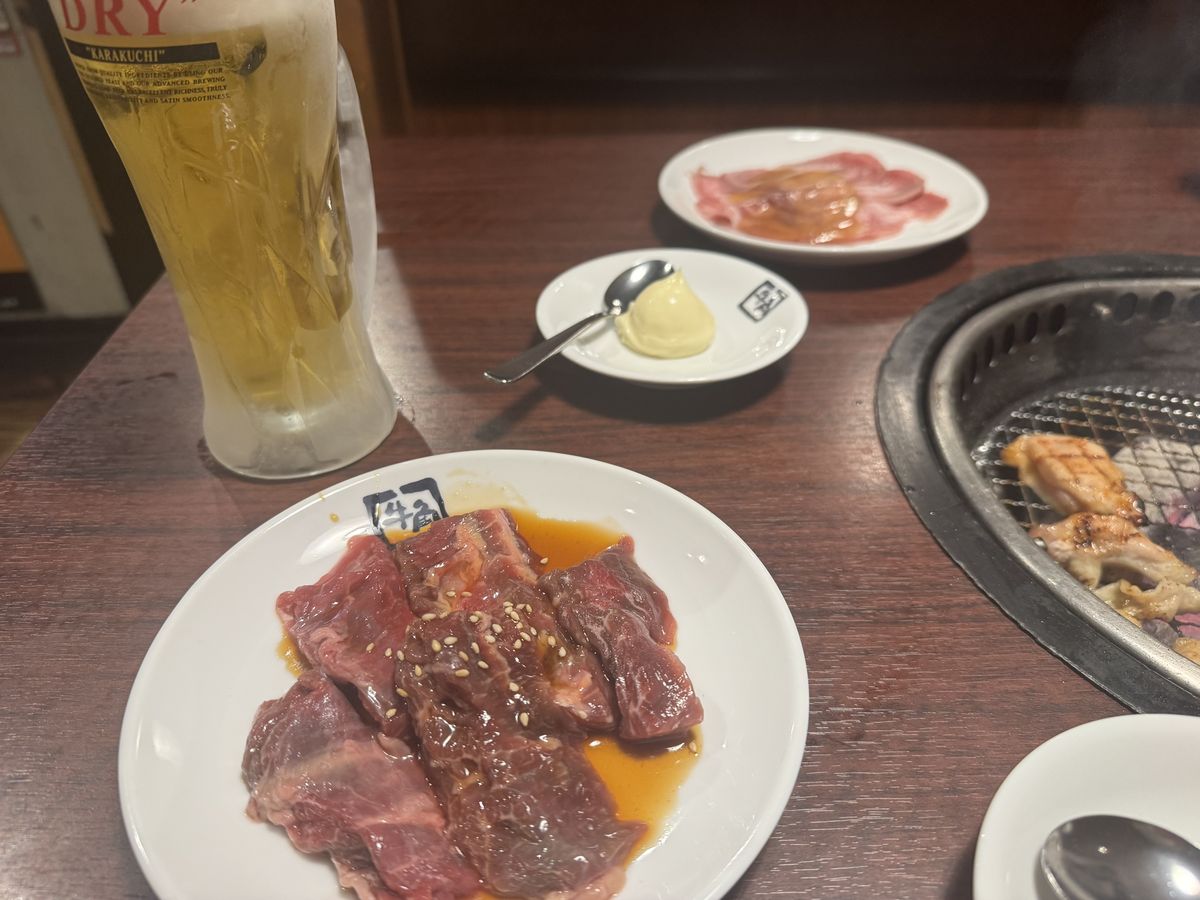 牛角のキンキンビールと肉料理。牛タンやハラミが盛られている