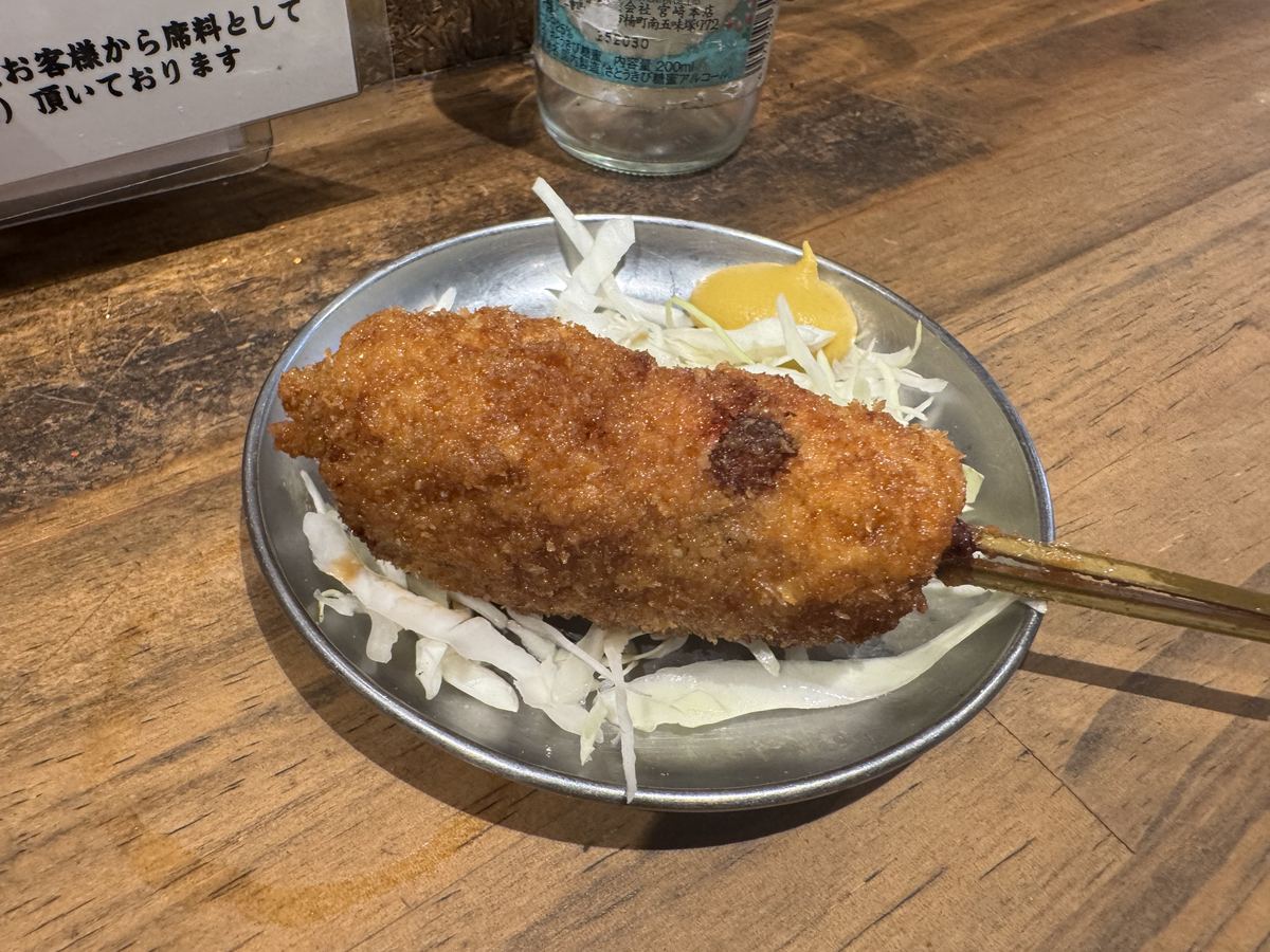おとんばの肉汁メンチ棒カツ串。千切りキャベツと辛子が添えられている
