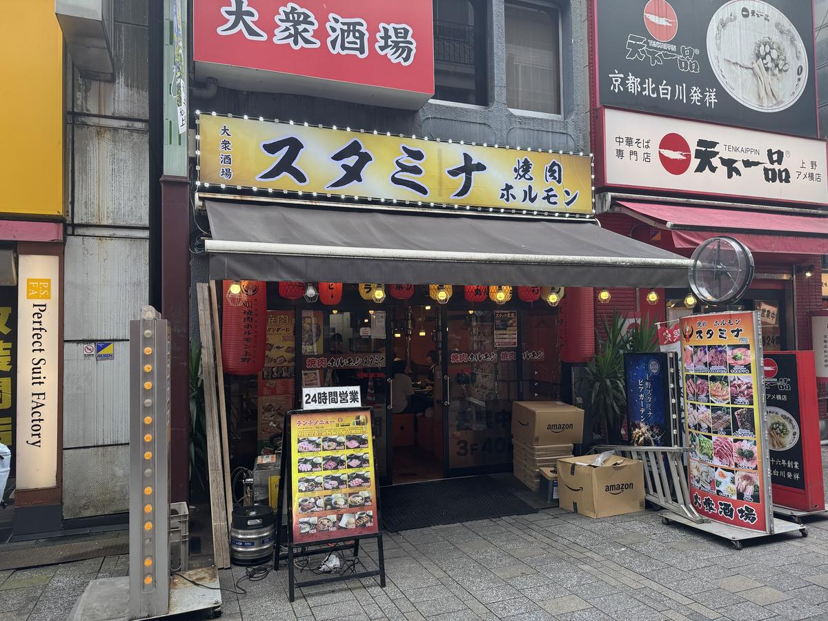 焼肉・ホルモン スタミナ上野店の店先。大きな黄色い看板と赤提灯が並ぶ